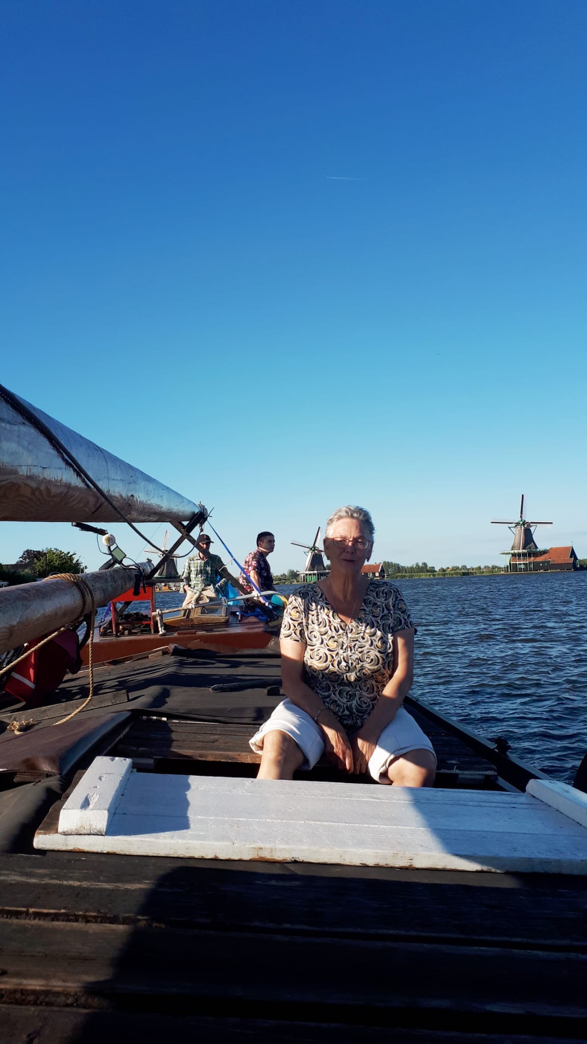 A guest on deck, windmills of the Zaanse Schans behind